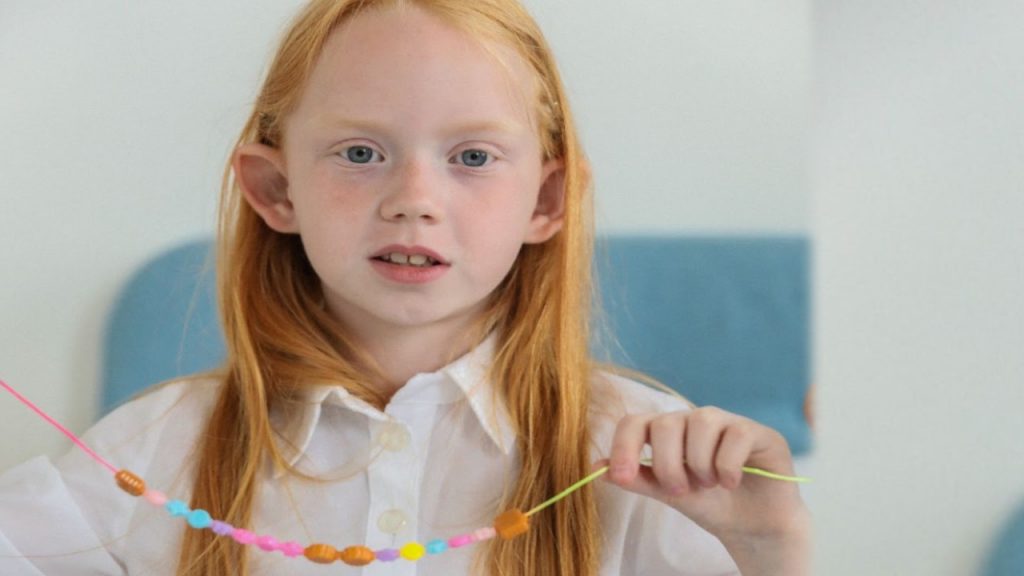 A girl displaying beads on a thread