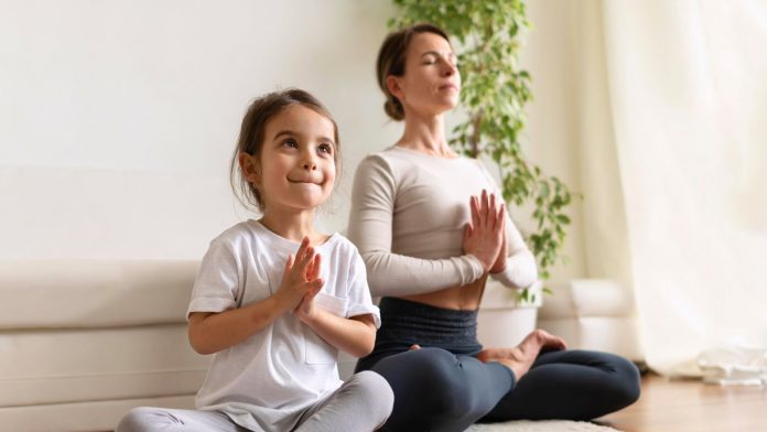 Little girl meditating with a woman
