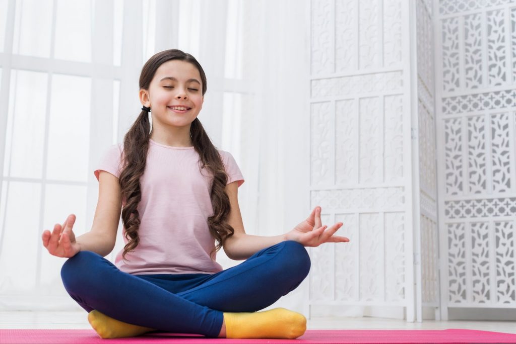 Little girl meditating on a yoga mat