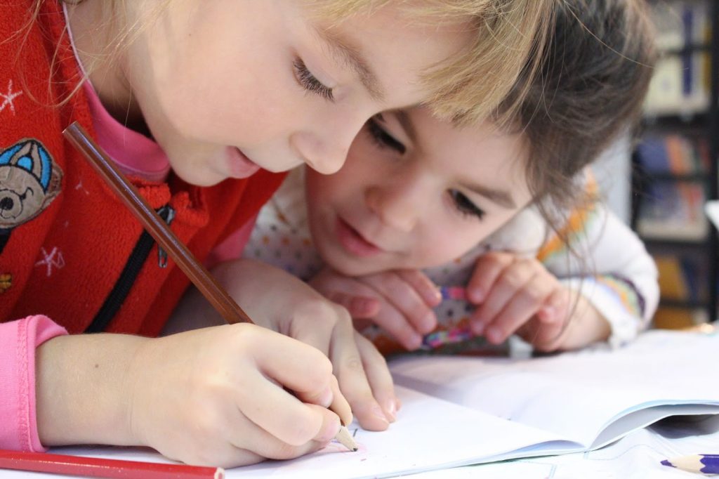 Two children writing something in a notebook