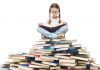 16 Best Reading Activities for Kids: Raising Young Readers Kid sitting on a pile of books and reading
