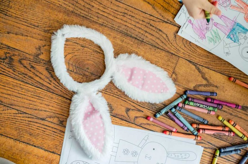 Headband with rabbit ears and coloring book placed on floor