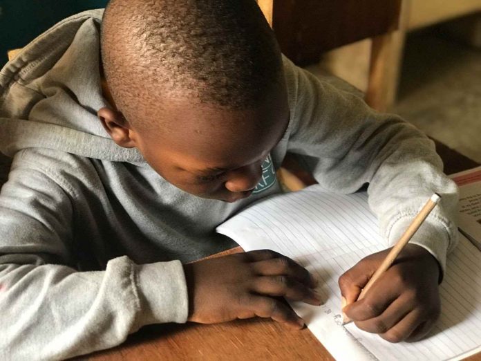 Photo of a Boy Writing in His Notebook at School