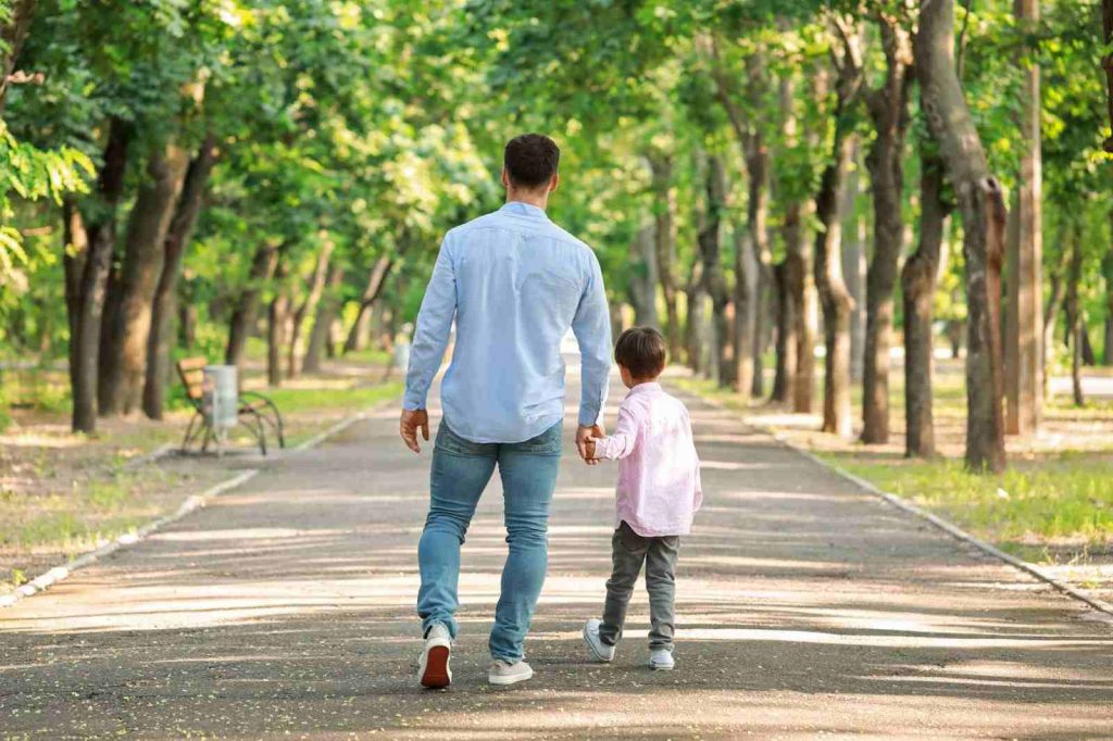 Kid walking with father in park