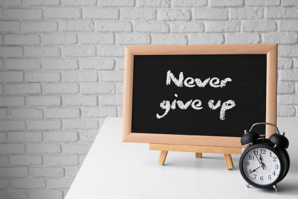 Small board with never give up written on it