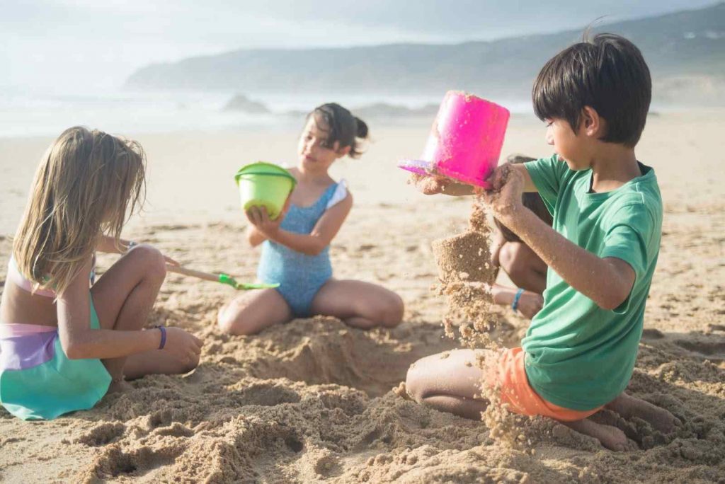 Three children playing with sand and water