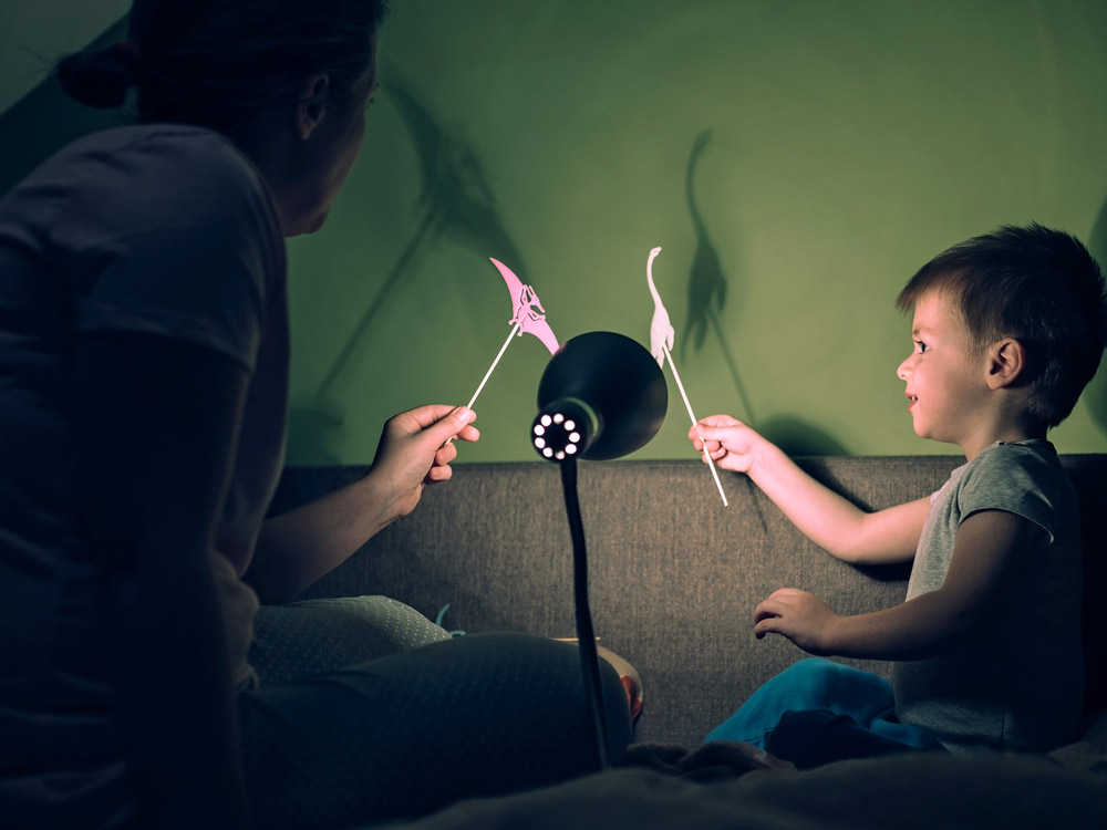 Kid with parents using light to create shadow in wall