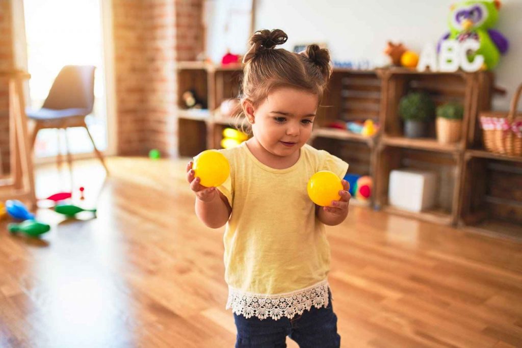 A young kid holding two balls