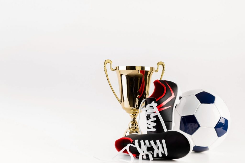 Football composition with shoes ball and trophy