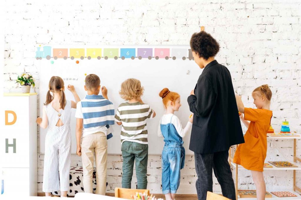 Students writing something on the board in the presence of the teacher