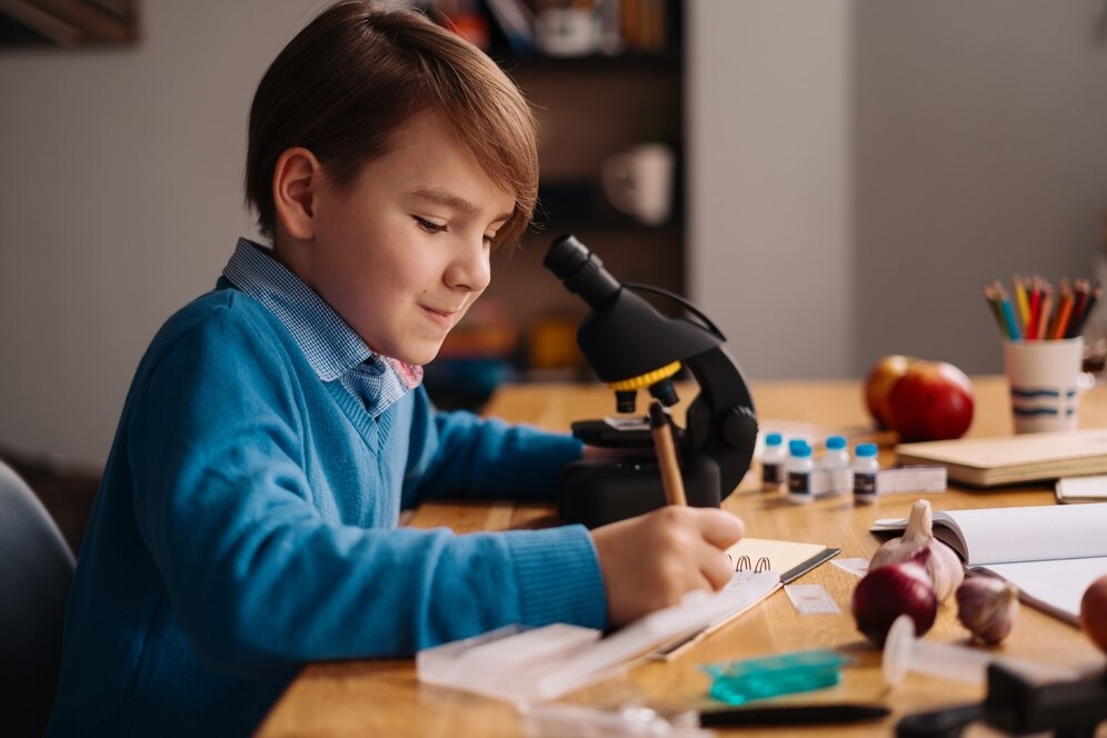 A boy studying at home using microscope