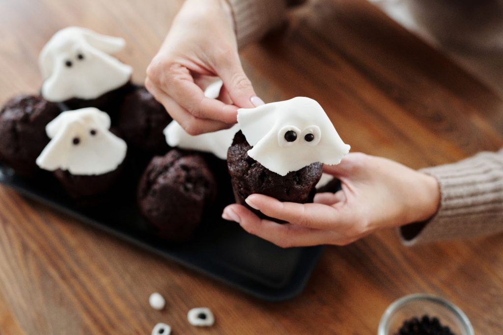 A woman holding a ghost-themed chocolate cupcake