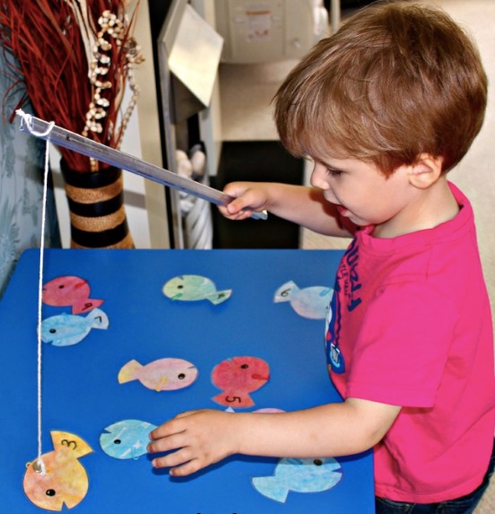 A boy using a fishing rod to catch numbered fish