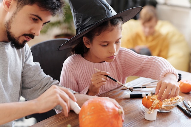 Father and daughter peeling and painting pumpkins