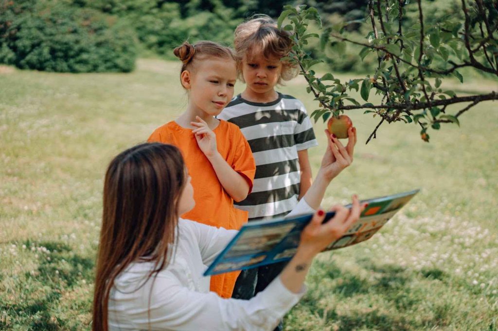 A mother picking apples with kids