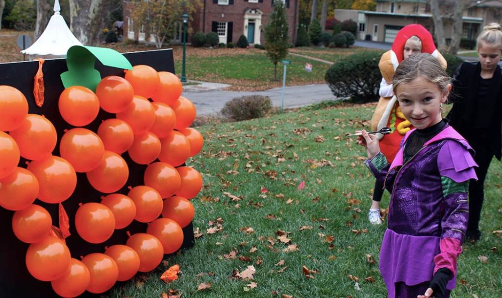 A girl holding a dart to play pumpkin pop