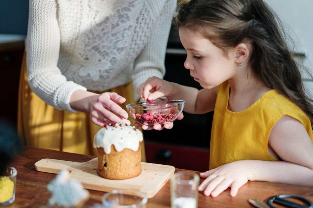 Kid putting decorations on a cupcake
