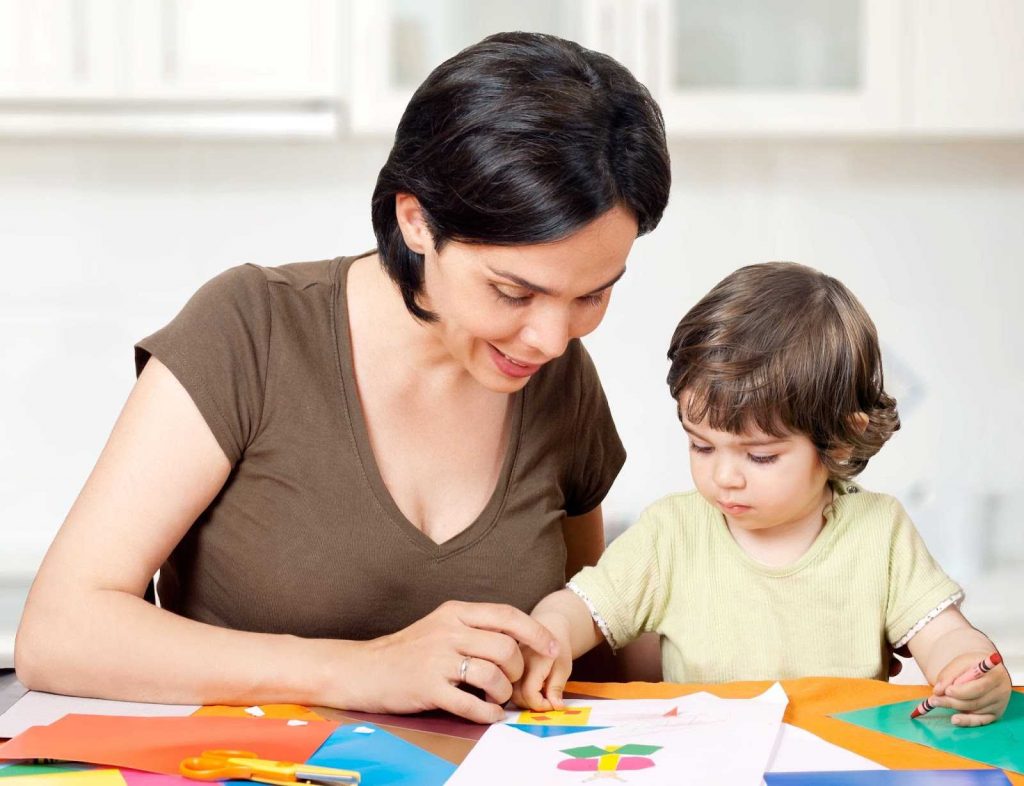 Kid making paper collage with mother