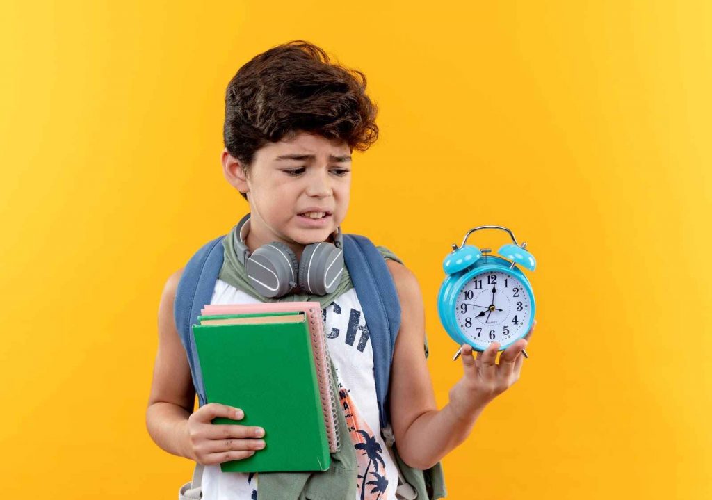 A boy holding books and an alarm