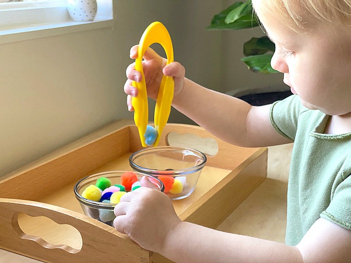 Kid using tong to pick small balls