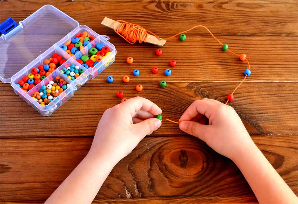 A kid putting beads in a string