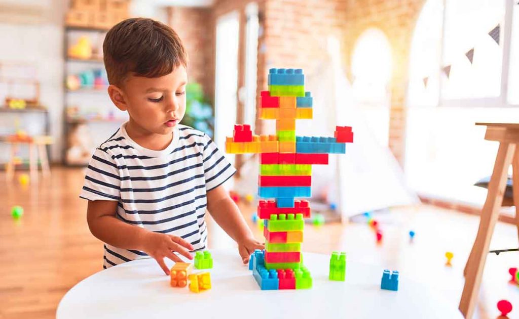 A kid building a tower with building blocks