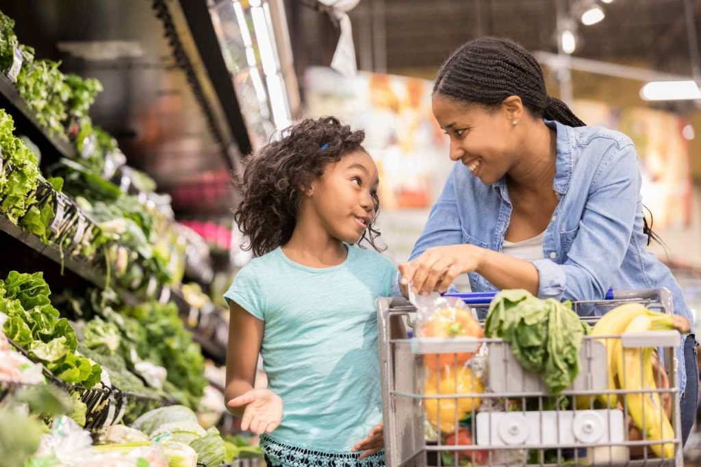 Mother and daughter looking at each other while grocery shopping