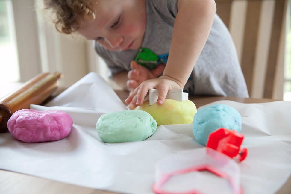 A boy pressing a star mold on a ball of clay dough