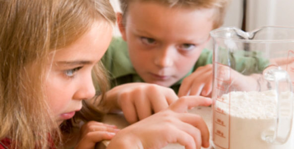 Two kids measuring flour