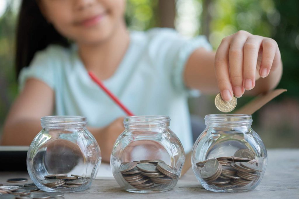 A kid putting coins in a jar