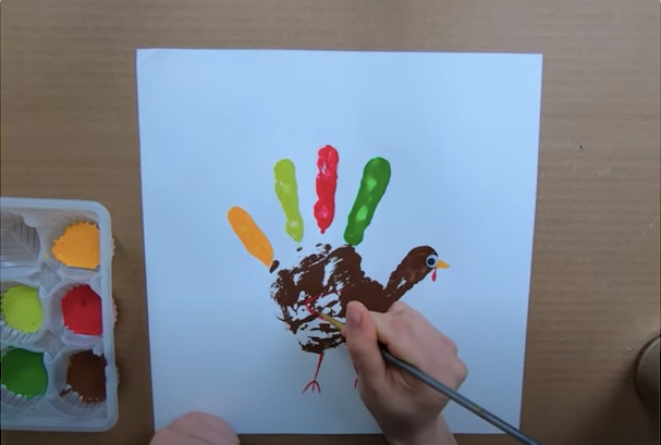 A person drawing on a hand turkey