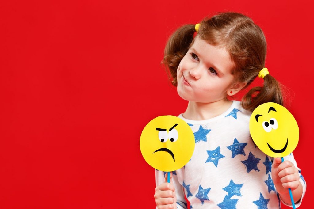 A girl holding emotion flashcards