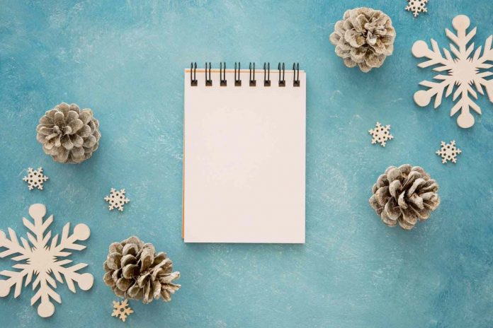 Top view of snowflakes, pinecone, and notebook