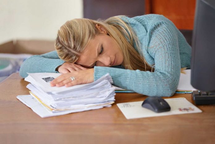 Teacher laying head on papers under stress