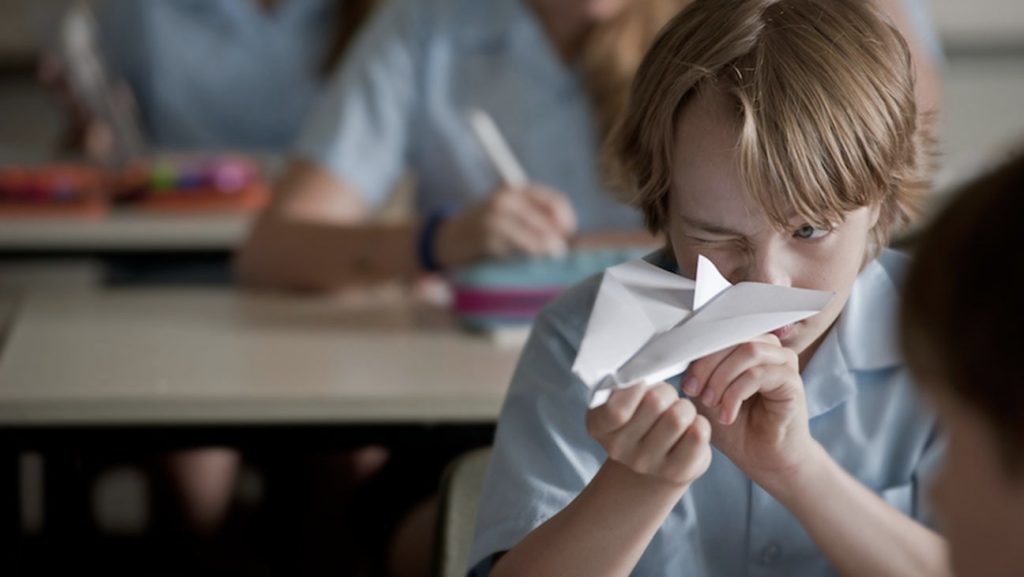 Kid flying a paper airplane in class