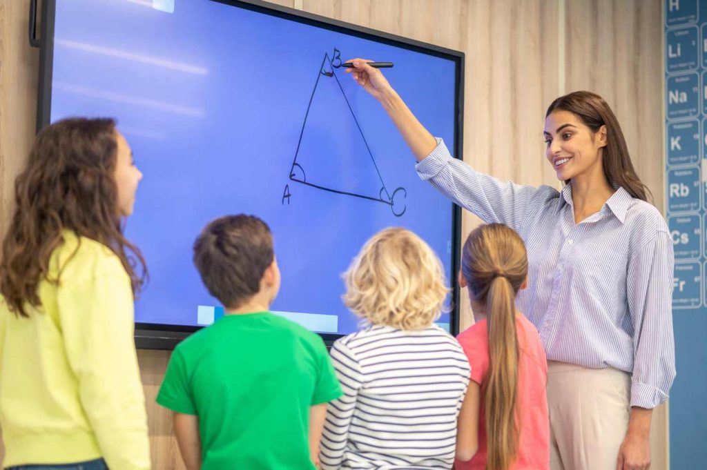 A Teacher teaching math problems to students on a smart board